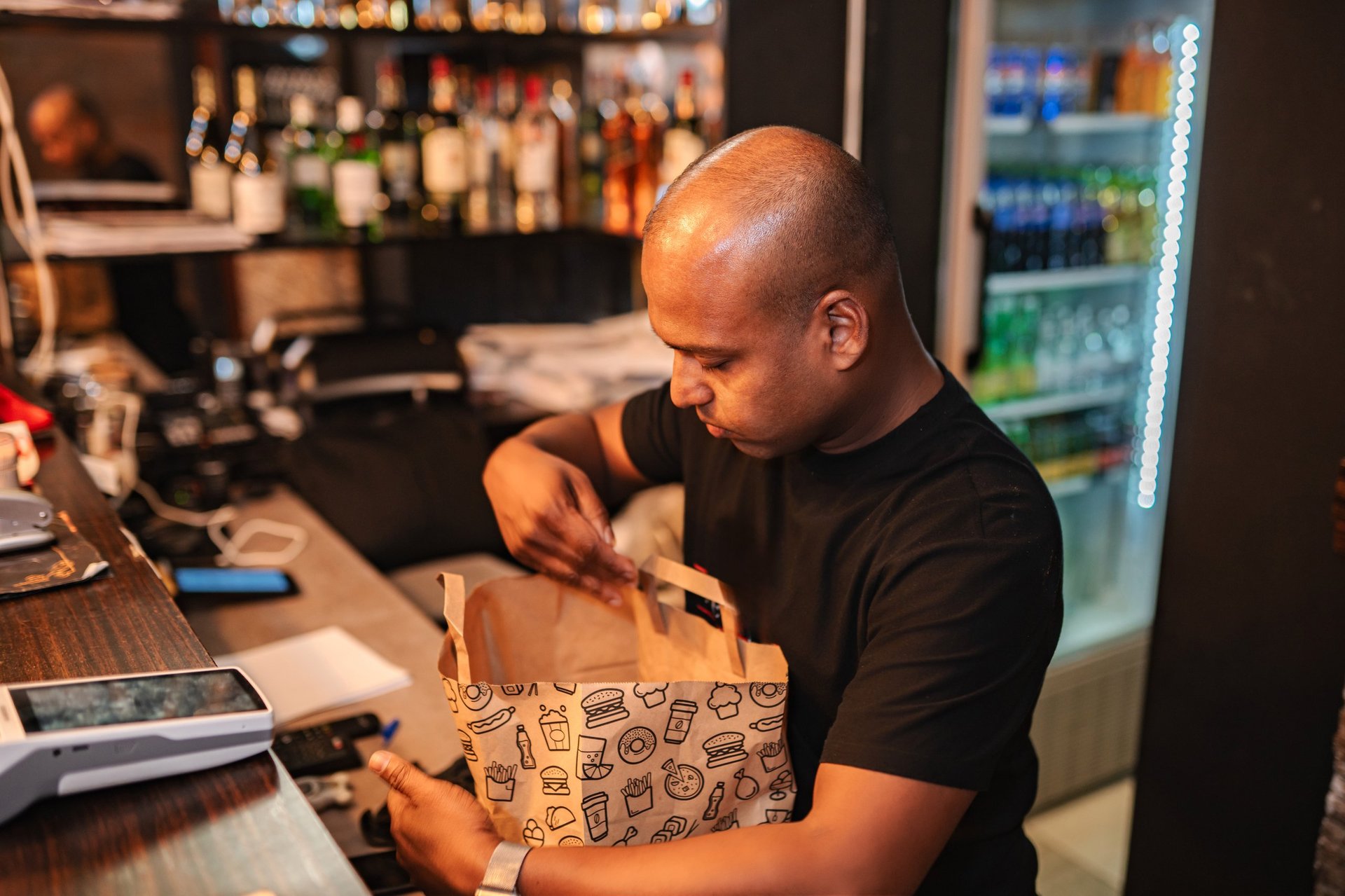 Restaurant employee packing food into a paper bag for a takeaway order